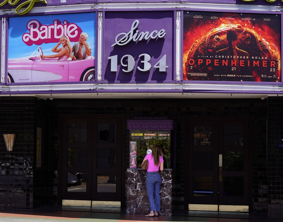 A patron buys a movie ticket underneath a marquee featuring the films